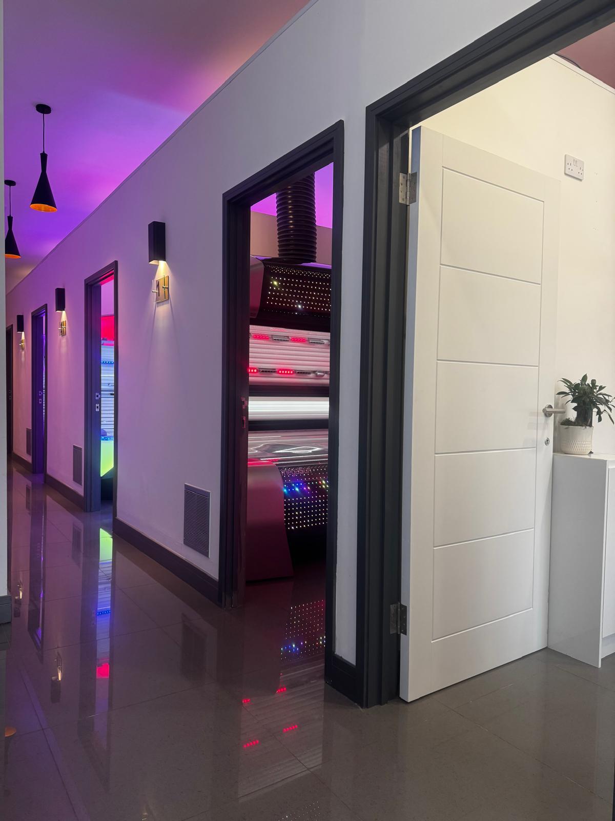 Afterglow Tanning interior — neon-lit private sunbed cabins